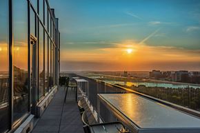 Boston apartment for rent - A sunset view from a high-rise building with a pool and chairs.