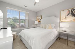 Charlotte apartment for rent - A bedroom with a large bed, a window with blinds, and a ceiling fan.