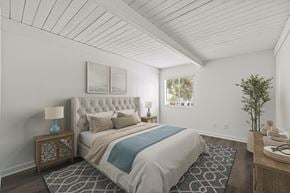 Montclair apartment for rent - A bedroom with a large bed and a small table with a lamp on it.