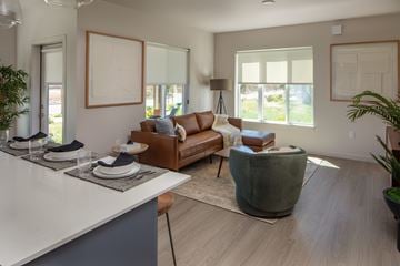 Vancouver apartment for rent - A modern living room with a brown leather couch and a grey armchair.