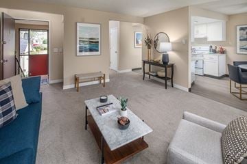 Tigard apartment for rent - A living room with a blue couch and a coffee table with a vase of flowers on it.