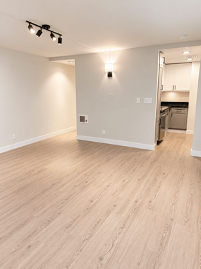 San Francisco apartment for rent - A room with a light on the wall and a kitchen in the background.