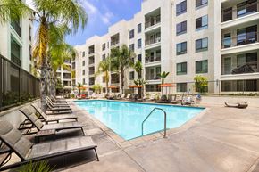 Monrovia apartment for rent - A pool surrounded by lounge chairs and palm trees.