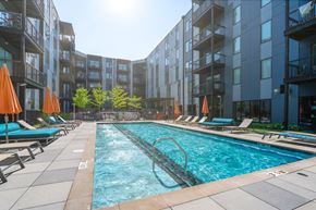 Louisville apartment for rent - A swimming pool surrounded by lounge chairs and umbrellas in front of apartment buildings.