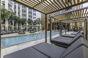 San Jose apartment for rent - A pool area with sun loungers and a wooden pergola.