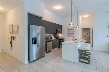 Miami apartment for rent - A modern kitchen with a stainless steel refrigerator and white countertops.