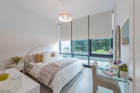 Miami apartment for rent - A bedroom with a large bed and a glass table with a plant on it.