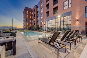 Salt Lake City apartment for rent - A pool area with lounge chairs and a building in the background.