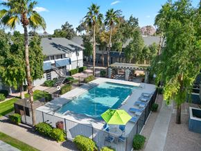 Phoenix apartment for rent - A pool surrounded by palm trees and bushes.