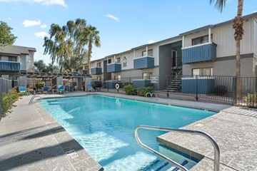 Phoenix apartment for rent - A swimming pool surrounded by a fence and palm trees.