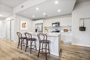 Miami apartment for rent - A kitchen with a white island and bar stools.