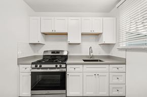 Daly City apartment for rent - A modern kitchen with white cabinets and a stainless steel stove top.