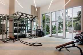 Oceanside apartment for rent - A gym with a variety of equipment including a squat rack, bench, and weights.