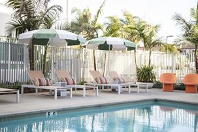Oceanside apartment for rent - A pool with chairs and umbrellas in the foreground.