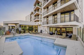 South Salt Lake apartment for rent - A large swimming pool is surrounded by a patio area with chairs and a hot tub.
