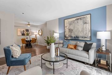 Elk Grove apartment for rent - A living room with a blue chair, a grey couch, and a large abstract painting on the wall.
