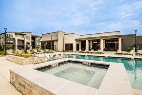 Wichita apartment for rent - A swimming pool in front of a building with a stone wall.