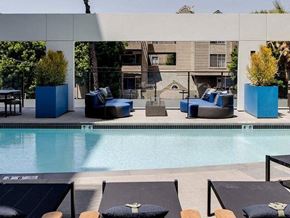 Long Beach apartment for rent - A pool with lounge chairs and a building in the background.