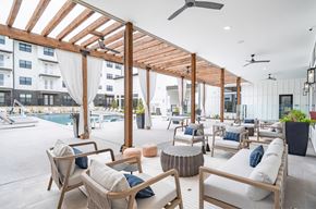 Austin apartment for rent - A patio with wooden furniture and a pool in the background.