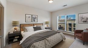 Atlanta apartment for rent - A bedroom with a large bed and a view of the city.