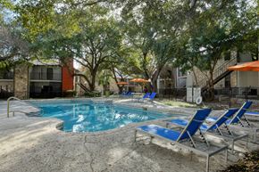 San Antonio apartment for rent - A pool surrounded by trees and chairs.