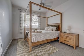 Farmington apartment for rent - A bedroom with a four-poster bed, striped bedspread, and a small nightstand with a lamp.