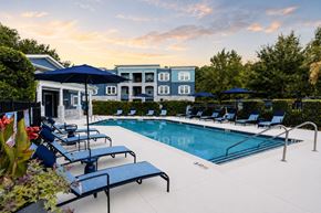 Charleston apartment for rent - A pool surrounded by lounge chairs and umbrellas with a building in the background.