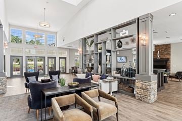Knightdale apartment for rent - A modern living room with a stone fireplace and a dining table with chairs.