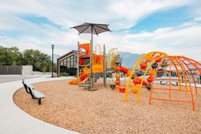 South Jordan townhouse for rent - A playground with orange and black equipment and a brown bench.