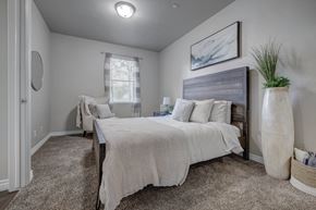 West Valley City apartment for rent - A bedroom with a large bed and a smaller bed in the background.
