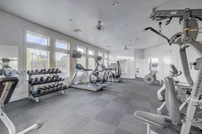 West Valley City apartment for rent - A gym with a variety of equipment including a treadmill, a stationary bike, and a weight rack.