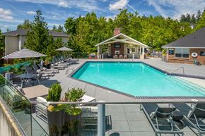 Tigard apartment for rent - A large swimming pool surrounded by lounge chairs and umbrellas.