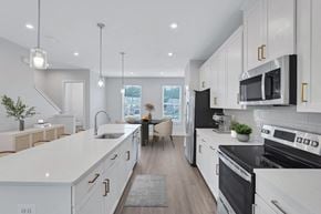 Waldorf apartment for rent - an open kitchen and dining room with white cabinets and black appliances