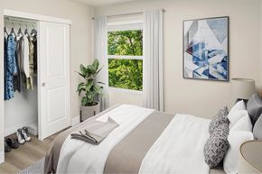 Tigard apartment for rent - A bedroom with a large bed and a window overlooking a green area.