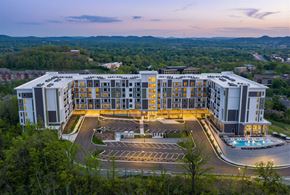 Brentwood apartment for rent - A large, modern building with a parking lot in front and a pool in the middle.