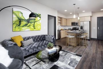 Anaheim apartment for rent - A modern living room with a grey couch and a green abstract painting on the wall.