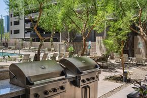 Phoenix apartment for rent - A grill is in the middle of a patio with trees and chairs around it.