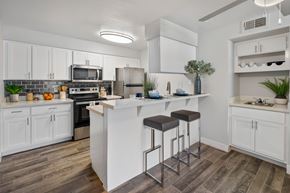 Mesa apartment for rent - A kitchen with white cabinets and a bar area.