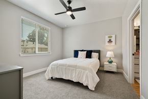 Boise apartment for rent - A bedroom with a white bed and a ceiling fan.