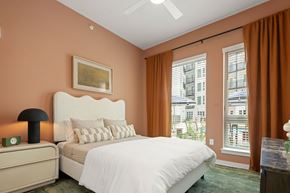 Charlotte apartment for rent - A bedroom with a large bed, a nightstand with a lamp, and a painting on the wall.