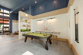 Charlotte apartment for rent - A pool table with a green felt cloth and a billiard ball rack is in the middle of the room.