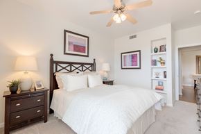 Aurora apartment for rent - A bedroom with a large bed, a ceiling fan, and a nightstand with a lamp.
