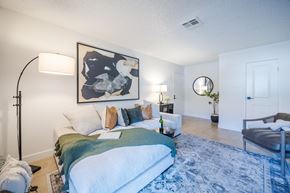 Henderson apartment for rent - A living space with a white sectional sofa, carpet, and lamps in an apartment at Sage at Green Valley.