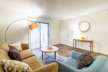 San Jose apartment for rent - A living room with a yellow couch, a blue chair, and a small table with candles on it.