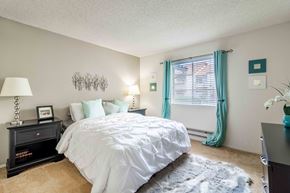 San Jose apartment for rent - A bedroom with a white bed and a black nightstand.