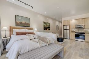 Lehi apartment for rent - A bedroom with two beds and a kitchen area in the background.
