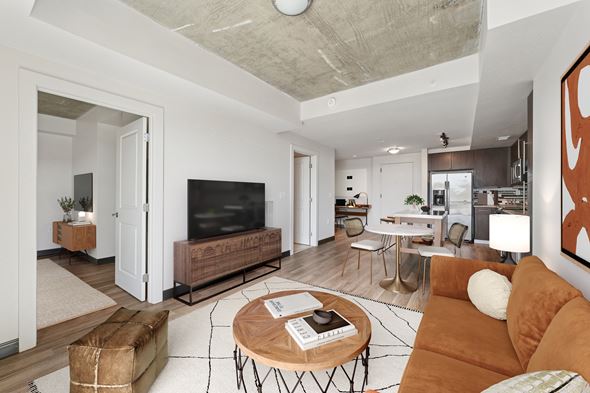 Washington apartment for rent - Modern apartment living room featuring a contemporary brown leather couch, wooden coffee table, and an open-concept layout leading into the kitchen and dining area.