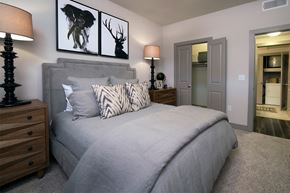 San Antonio apartment for rent - A bedroom with a large bed, two lamps, and a painting of a deer head on the wall.