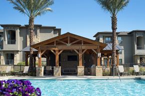 San Antonio apartment for rent - A pool area with a wooden pavilion and palm trees.