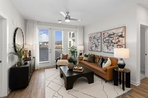 Charlotte apartment for rent - A living room with a brown couch, a coffee table, and a ceiling fan.